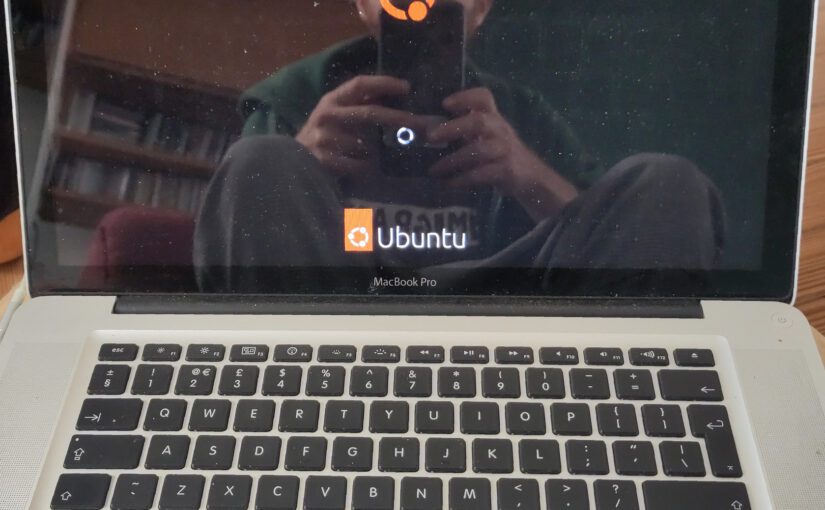 The Ubuntu logo on a Mac screen. The photographer is visible in the reflection.