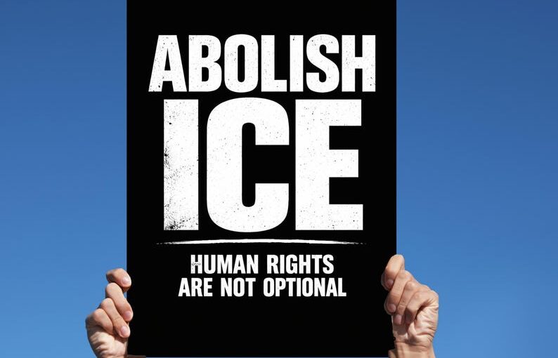 White hands holding up a protest sign which says "Abolish ICE. Human rights are not optional."